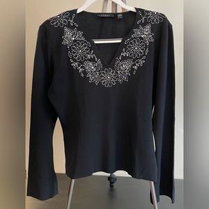 Women’s black v-neck sweater with white floral design at neckline.